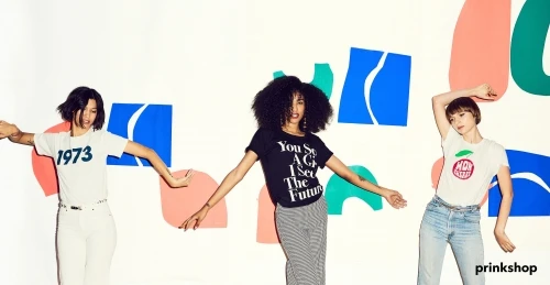 Three diverse women pose in a studio with colorful graphic backgrounds wearing casual t-shirts and bottoms, capturing a modern, youthful vibe.