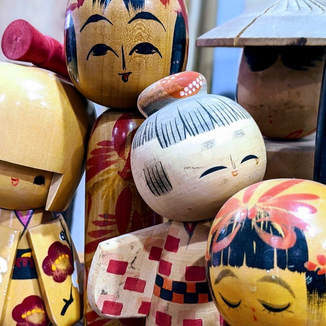 Close-up of a collection of traditional Japanese kokeshi dolls, handcrafted from wood with painted faces and kimono-like designs.