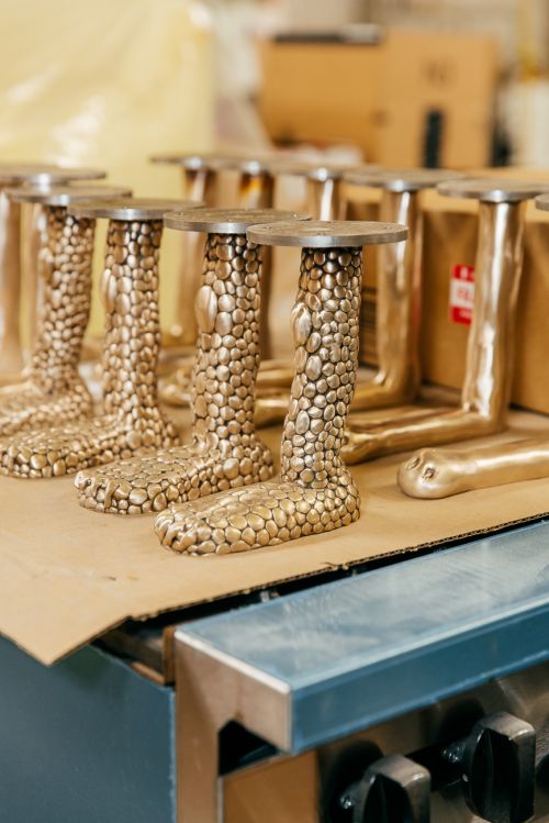 Close-up of a group of similar bronze objects with round bases and textured columns resembling legs or organic forms in a production setting.