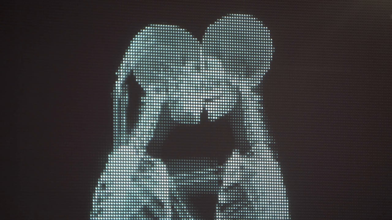 Pixelated image of two figures, likely adults, creating a heart shape with their heads on a dark background, possibly a digital art piece.