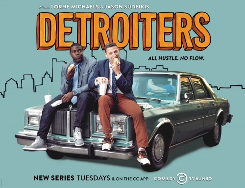 Two men sit atop a vintage car, styled in suits, eating sandwiches, promoting the 'Detroiters' TV series against a teal backdrop.