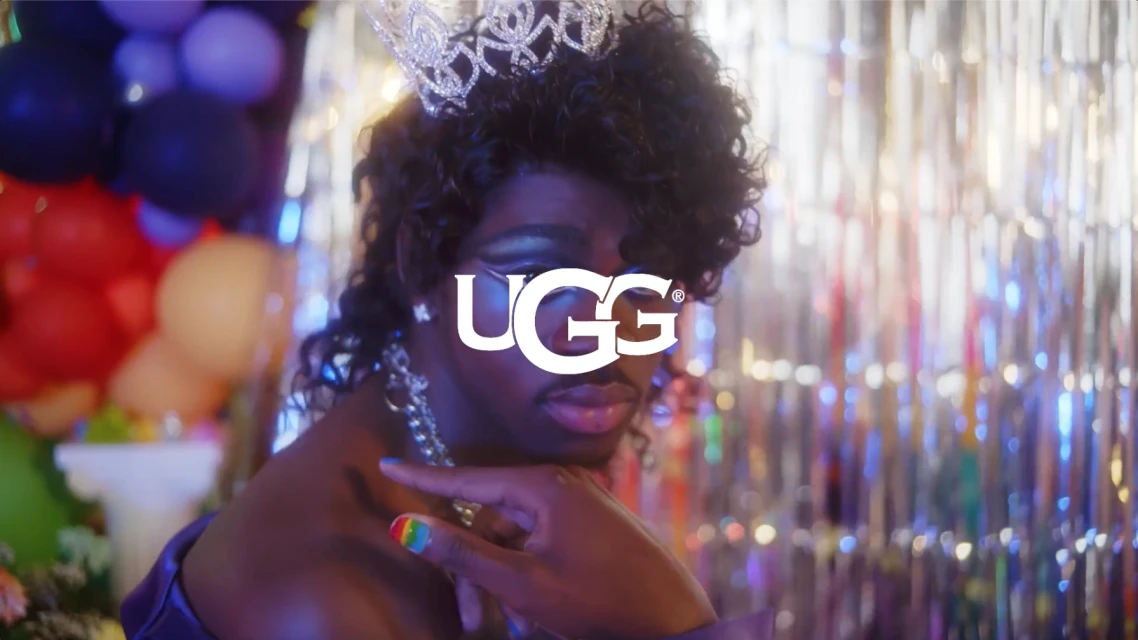 Close-up shot of a person wearing a tiara and jewelry, with balloons in the background and the 'UGG' logo superimposed on the image.