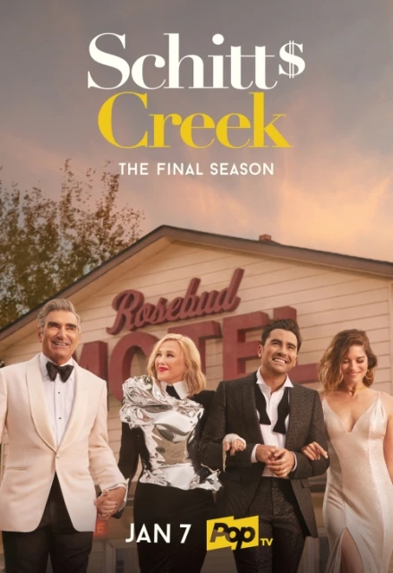 Promotional shot from Schitt's Creek showing four smiling adults in formal wear standing in front of the Rosebud Motel building.