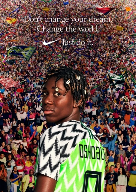 Close up of a Black woman wearing a Nigeria soccer jersey in front of a crowd with Nike logo and slogan on top, promoting sports.