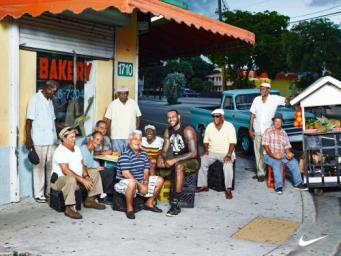 LeBron James seated outdoors among a group of men outside a bakery next to a blue vintage truck.