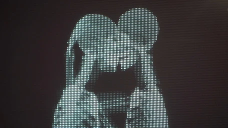 Close-up of two silhouetted figures kissing, rendered in bright white dot matrix display against a dark grid background.