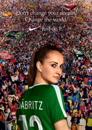 Female soccer player in a green jersey looking back over her shoulder against a massive dense crowd in a stadium.