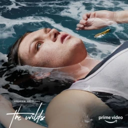Young woman floating on her back in churning dark blue water, with foam around her head and a small gold tube floating nearby.