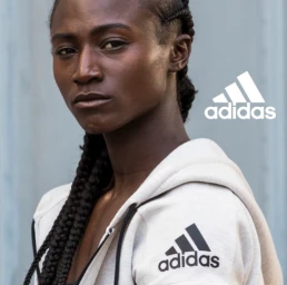 Close-up portrait of a Black woman wearing an off-white hoodie with black drawstrings and an Adidas logo by director Danielle Levitt