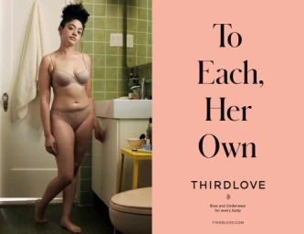 Woman in beige lingerie standing in a bathroom next to a green tiled wall and a white vanity