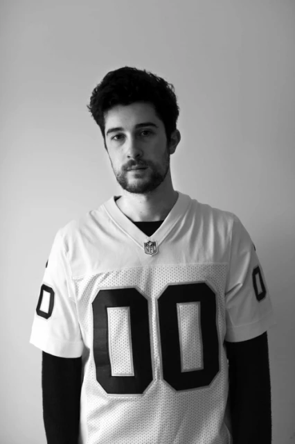 Portrait of a young adult male wearing an NFL jersey in a black and white photo, showcasing fashion and sports themes.