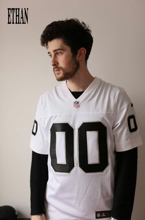 Adult male with black hair wearing a white NFL jersey with the number 00 in an indoor setting, portrait orientation.