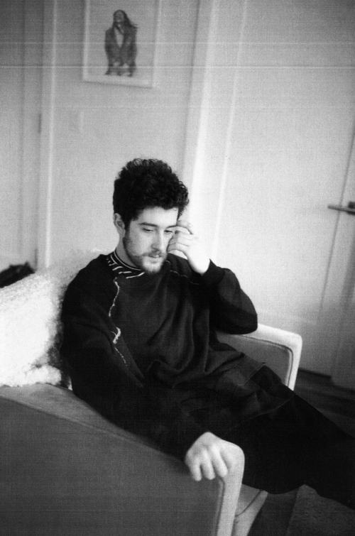 Monochrome portrait of a man seated in an armchair with hand to face, photographed in New York by Ari Marcopoulos.