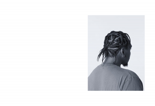 Monochrome headshot from behind of a Black male adult wearing cornrows. Close-up studio shot with shallow depth of field, and soft lighting.
