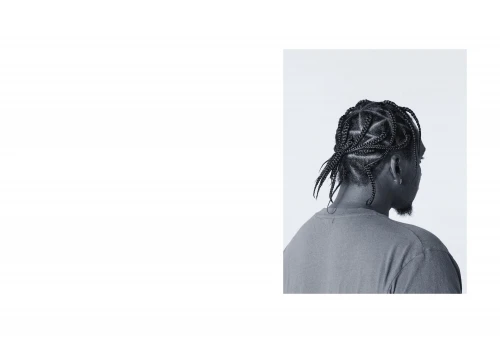 Monochrome headshot from behind of a Black male adult wearing cornrows. Close-up studio shot with shallow depth of field, and soft lighting.