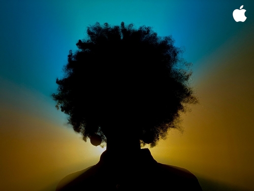 Silhouette of a person with an afro hairstyle against a blue and yellow gradient background with an Apple logo in the upper right.
