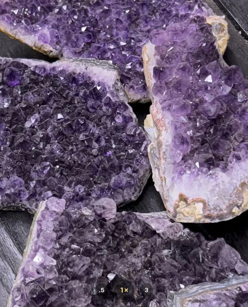 Amethyst crystal cluster pieces with a dark purple color, rough texture, and white accents, filling the frame in an eye-level shot.