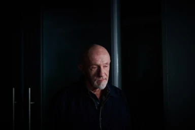Portrait of an elderly man with a white goatee in a dark room photographed by Jake Michaels.