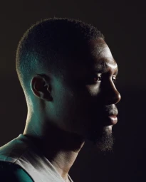 Profile portrait of a Black man in profile with dramatic side lighting and a teal backlight by Jake Michaels.