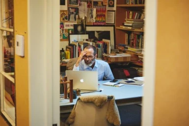 Man with glasses sitting at a desk with a laptop in a home office photographed by Jake Michaels