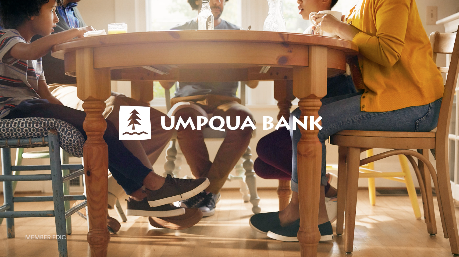 Family sits around a wooden table at home, enjoying a meal together in a warm, inviting setting during the daytime with natural light.