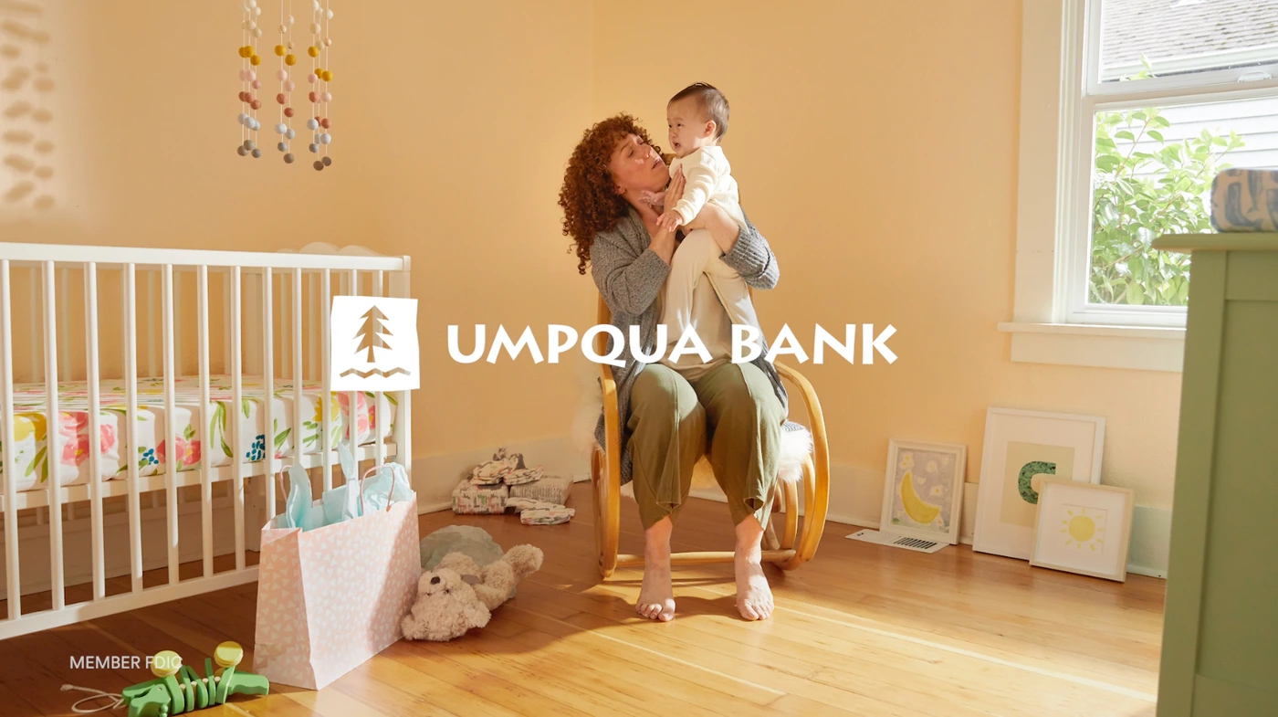 A woman holding a baby in a nursery with a rocking chair and a crib photographed by Christa Renee.