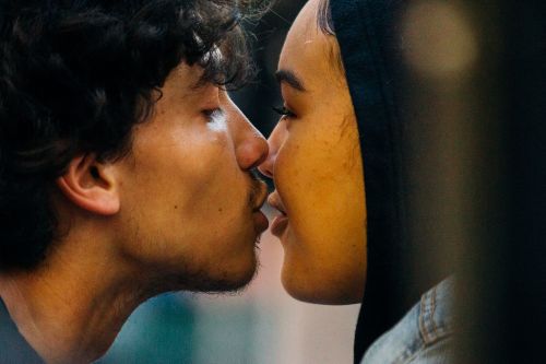 Close-up shot of a biracial couple, a man and a woman, in a loving embrace, faces touching, with soft natural lighting.