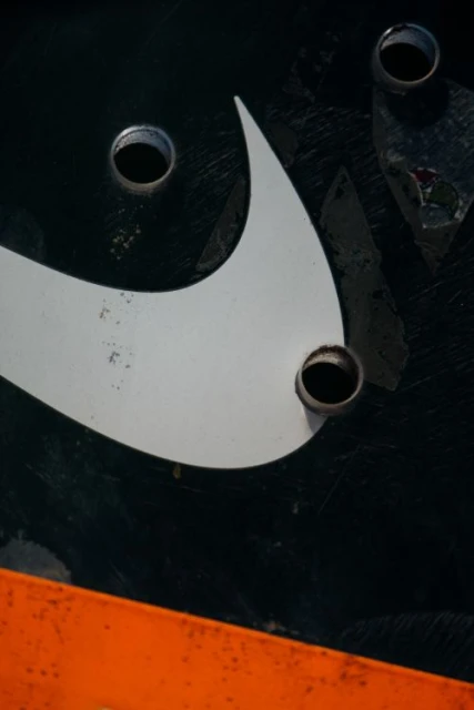 Close-up abstract shot of a fragment of a logo with drilled holes on a black background with an orange section visible.