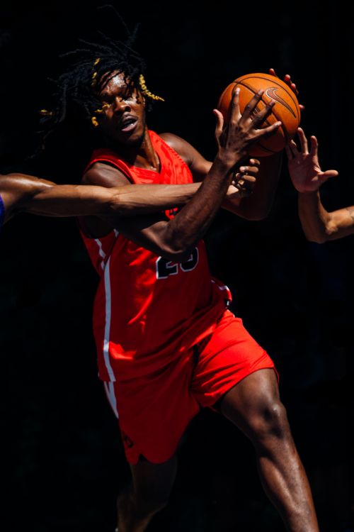 African American basketball player dribbling the ball while other players try to take it away from him in action shot.