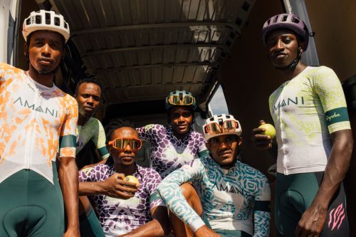 Group of six African cyclists in team kits pose inside vehicle, holding fruit, showcasing sports, teamwork, and healthy lifestyle.