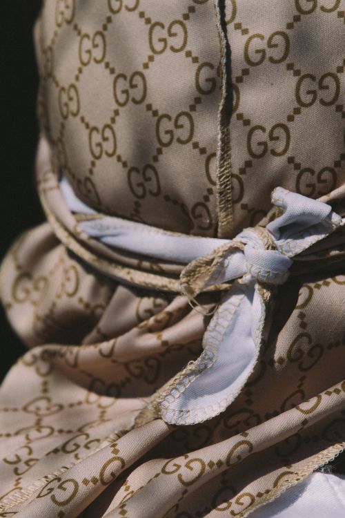 Close-up of a person wearing a beige monogram-patterned durag tied with a white headband, photographed by Alessandro Simonetti.