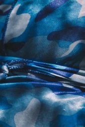 Close-up of blue camouflage satin fabric with gathered folds and drawstring detail photographed by Alessandro Simonetti