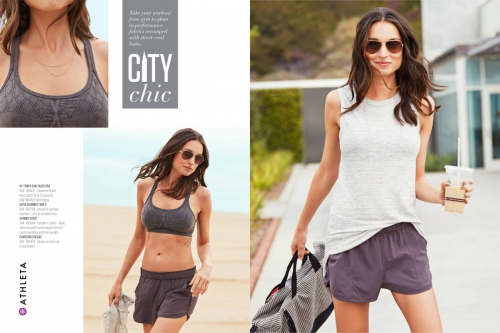 Athleta marketing image: A woman in a grey tank top and purple shorts holds a drink and bag on a city street, smiling at the camera.
