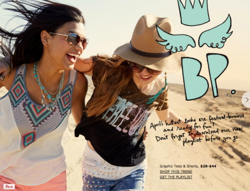 Two smiling young women walking together on a sandy beach wearing casual festival fashion with sunglasses and a straw hat.