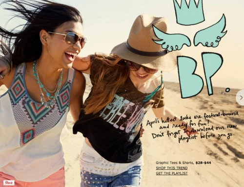 Two smiling young women walking together on a sandy beach wearing casual festival fashion with sunglasses and a straw hat.