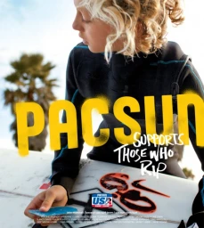 Young surfer with curly blonde hair wearing a black wetsuit holding a wax scraper over a surfboard with text overlay.
