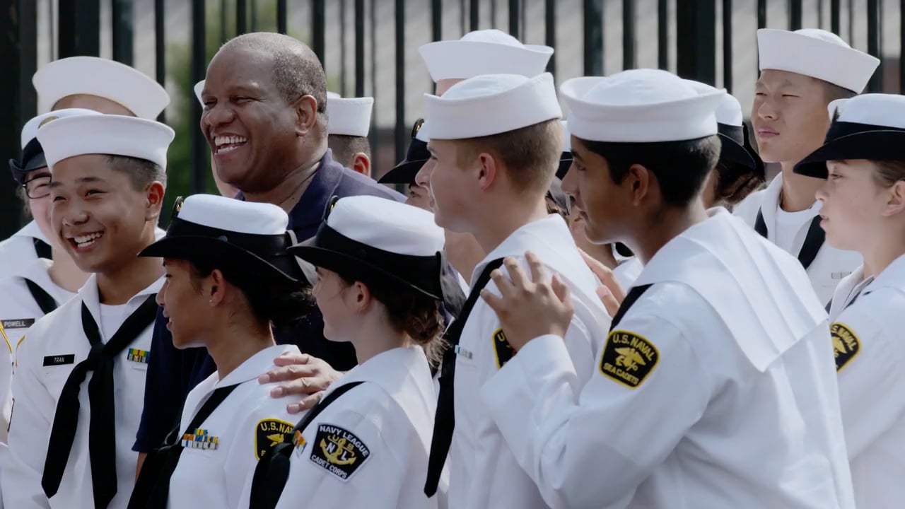 Group of smiling naval cadets in white uniforms standing together outdoors photographed by Peter Yang.