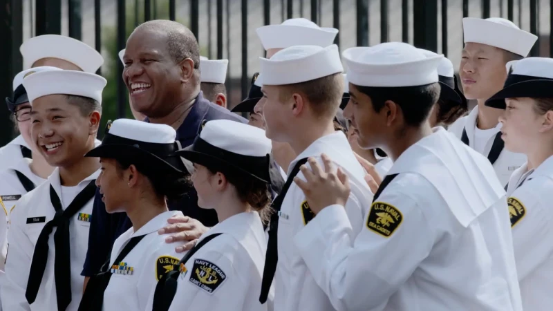 Group of smiling naval cadets in white uniforms standing together outdoors photographed by Peter Yang.