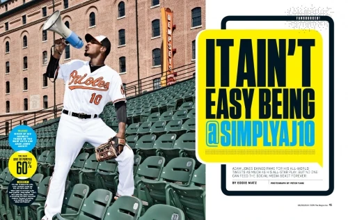Baseball player in Orioles uniform drinking from a megaphone on stadium seating.  Close-up with stadium architecture in background.