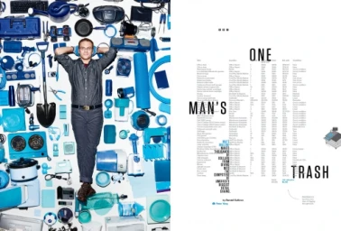 Man lying on a white surface surrounded by an arrangement of various blue objects and household items.