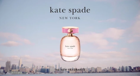 A perfume bottle with a pink cap floating against a soft sky and a New York City skyline background.