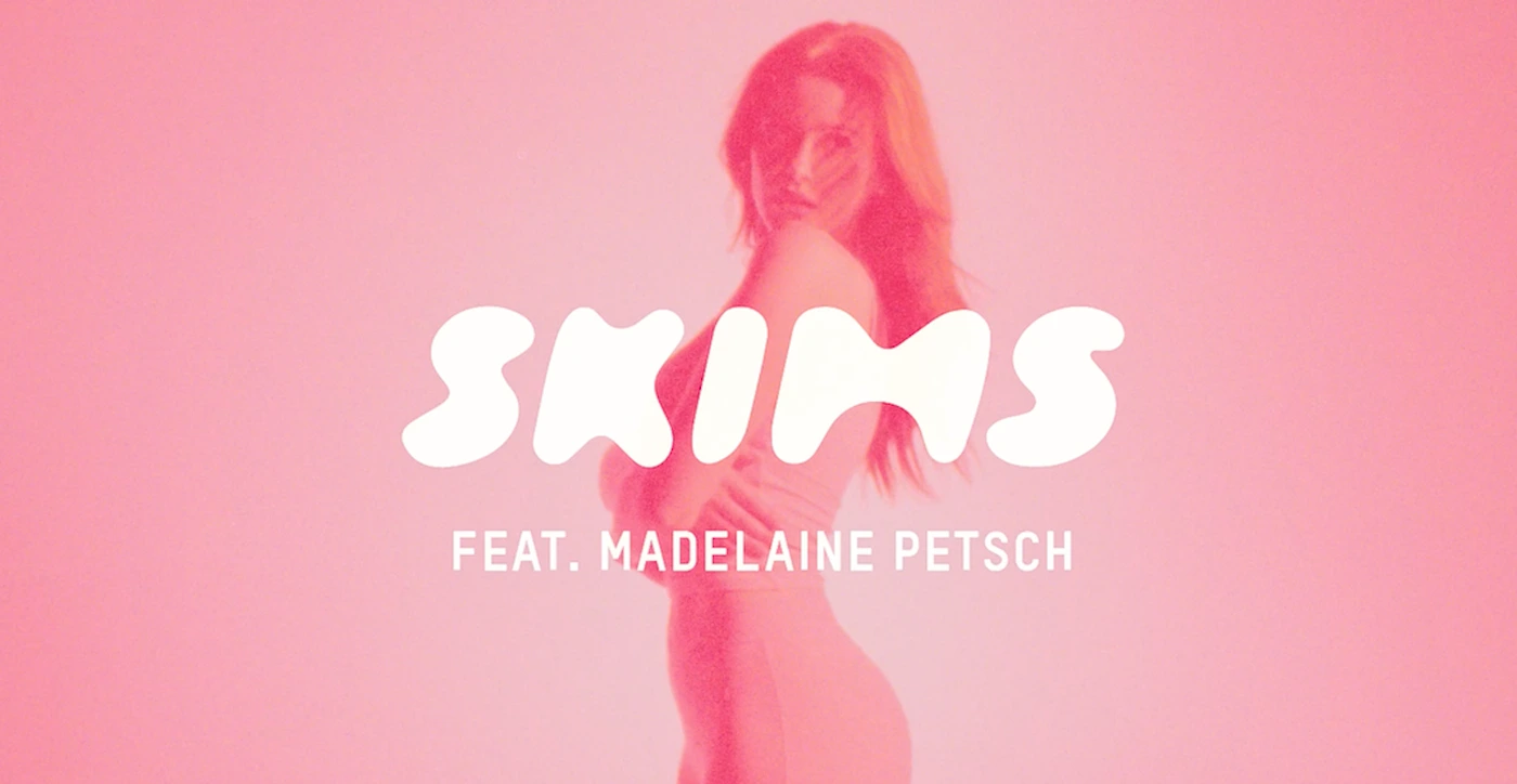 Madelaine Petsch posing in a pink-toned commercial frame with large white Skims typography overlay.