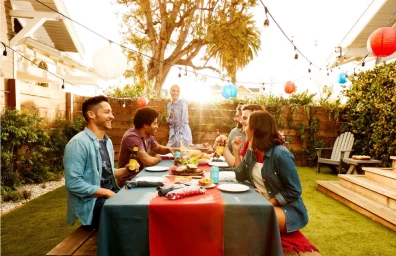 Group of diverse friends gathered around an outdoor dinner table with string lights and paper lanterns in Los Angeles.