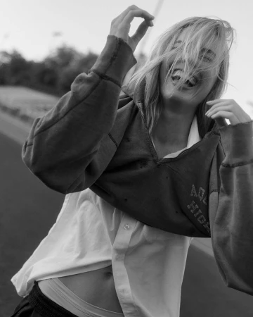 Black and white portrait of a laughing woman wearing a hooded sweatshirt and layered shirt by photographer Lindsey Childs.