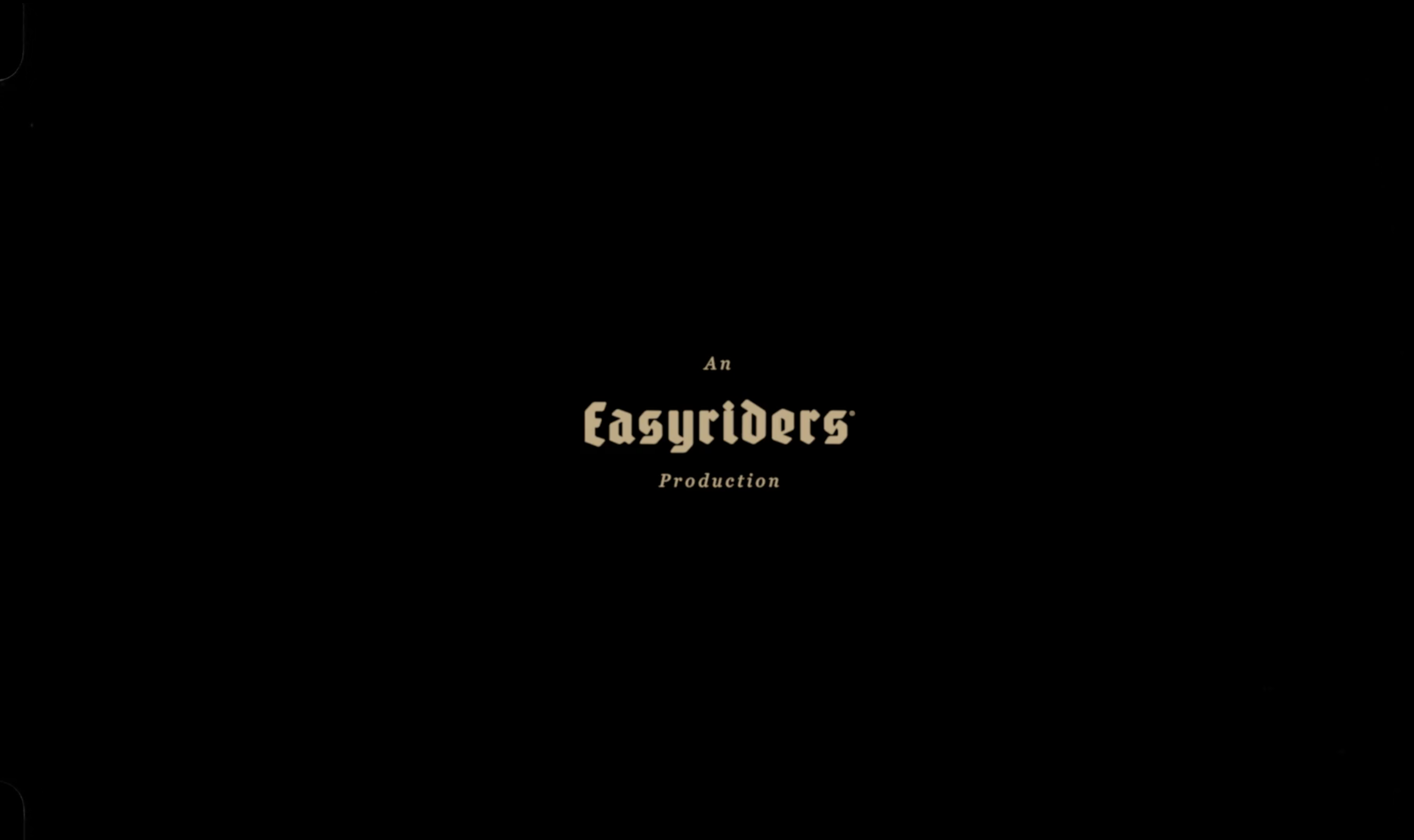 Black screen with tan-colored text: 'An Easyriders Production' centered on the screen. Minimalist, cinematic, production still.