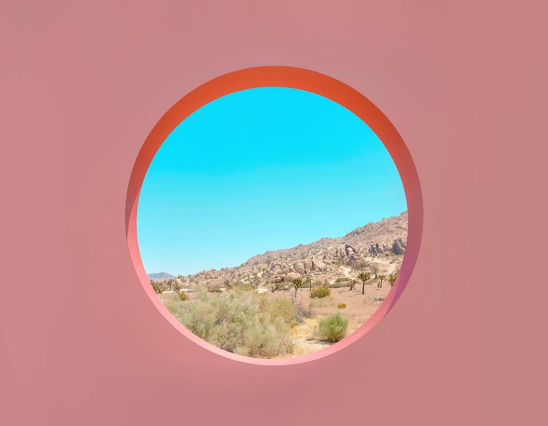 Desert landscape with rock formations viewed through a coral pink circular frame, showcasing natural beauty and unique perspective.