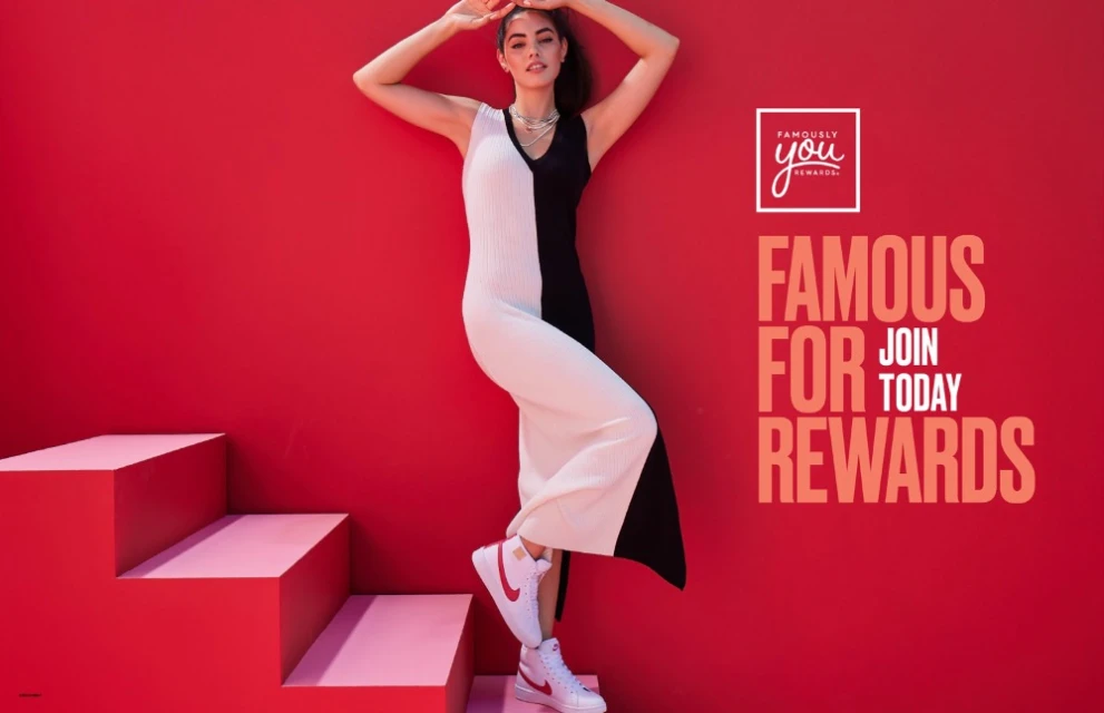 A woman in a black and white dress and red sneakers stands on a red staircase in front of a red background for a fashion advertisement.