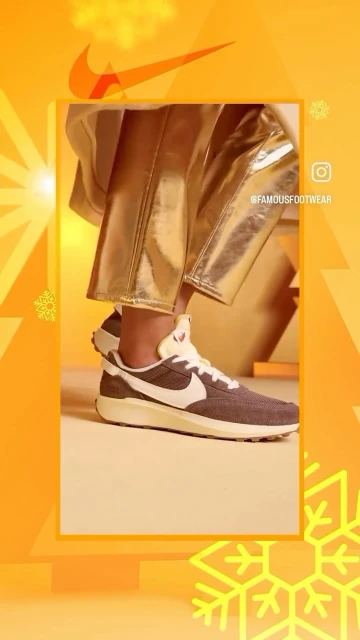 Tan and gray Nike sneaker on a woman's feet, paired with shiny gold pants, against a vibrant orange background with snowflake accents.