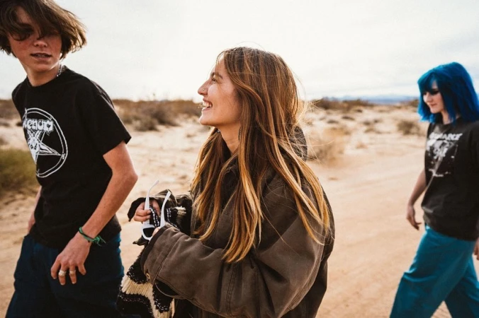 Three young people walking together outdoors in a desert landscape under a clear sky.