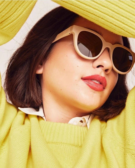 Woman wearing sunglasses and a yellow sweater. Close-up portrait of a fashionable model with dark hair and coral lipstick.